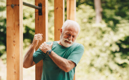 A senior man suffers from shoulder pain during a workout.