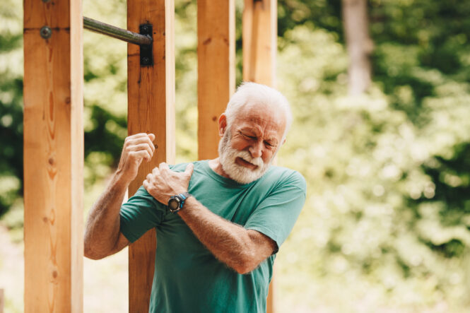 A senior man suffers from shoulder pain during a workout.