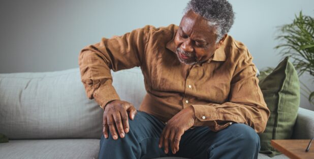 An older man with knee osteoarthritis rubs his knee.
