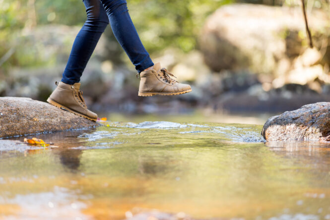 person stepping into a brook on a hike