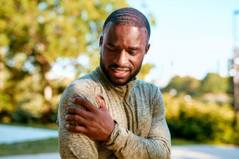 black man holding his right shoulder in pain