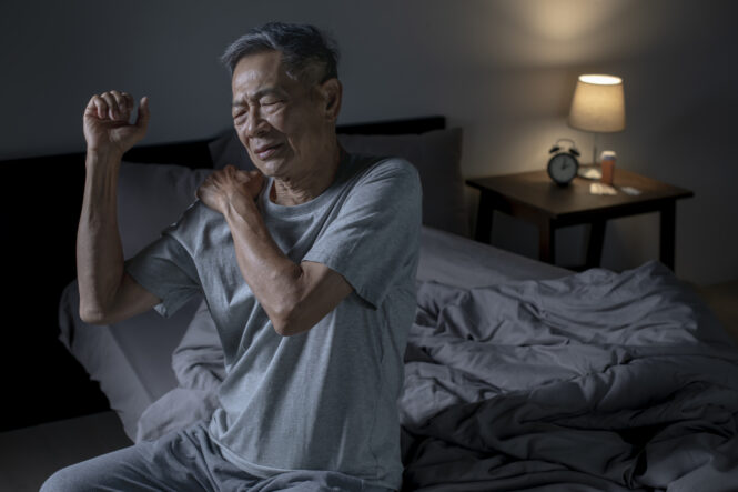 man hold his shoulder after waking up